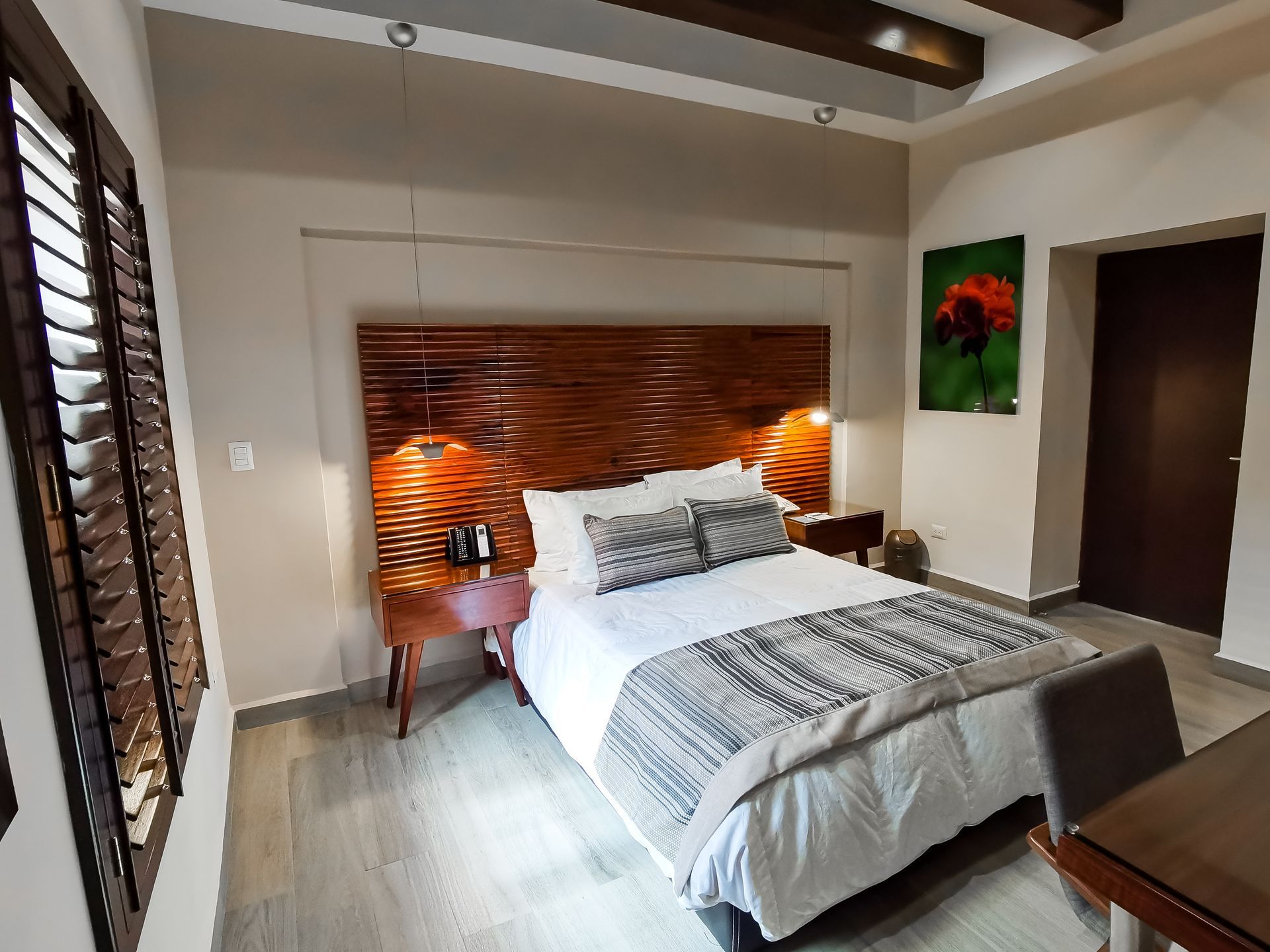 Una habitación de hotel con una cama tamaño king y una cabecera de madera.
