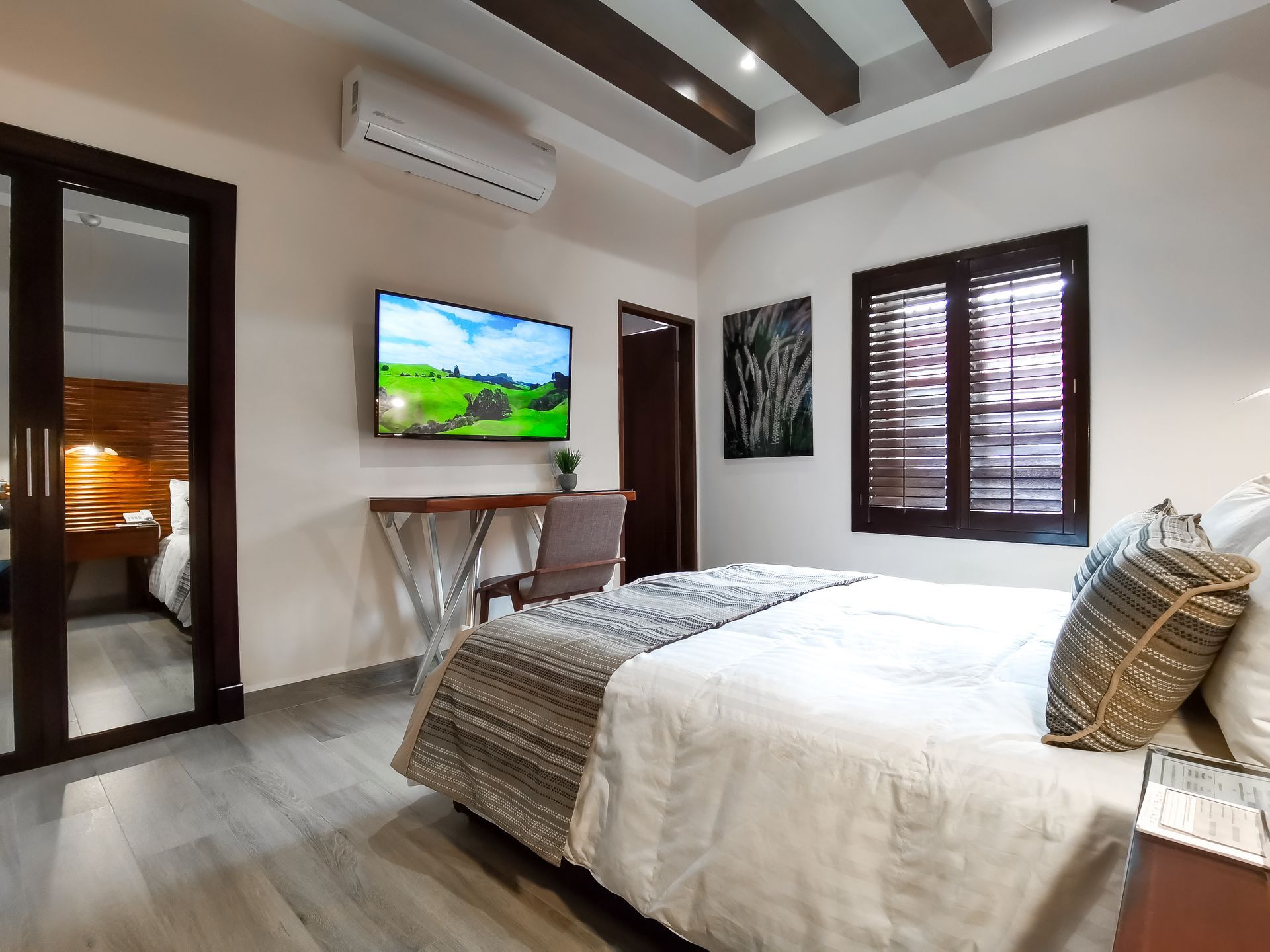 Un dormitorio con cama, televisión, escritorio y ventana.