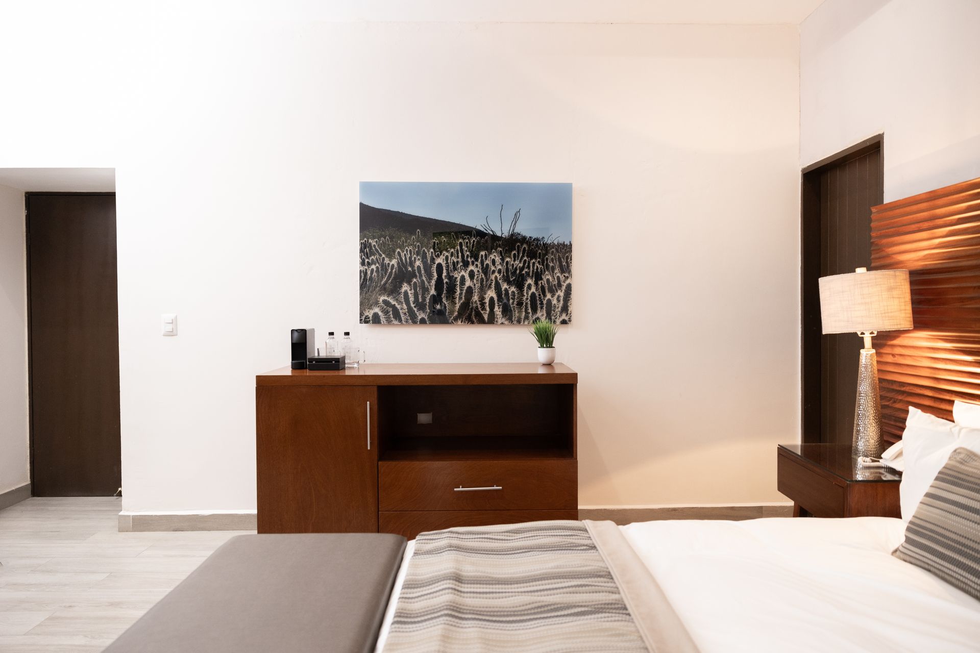 Un dormitorio con una cama, mesita de noche, lámpara y un cuadro en la pared.