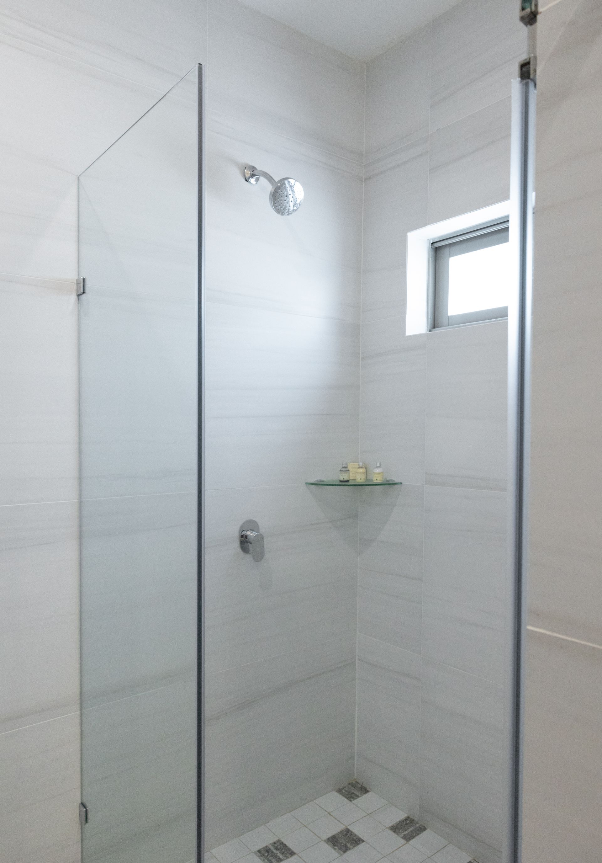 Un baño con puerta de ducha de cristal y una ventana.