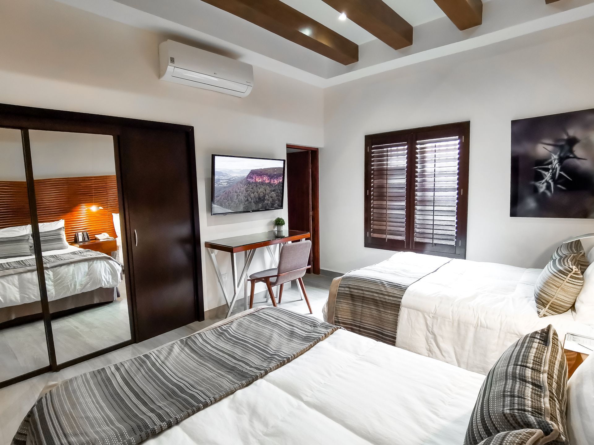 Una habitación de hotel con dos camas, un escritorio y un televisor.