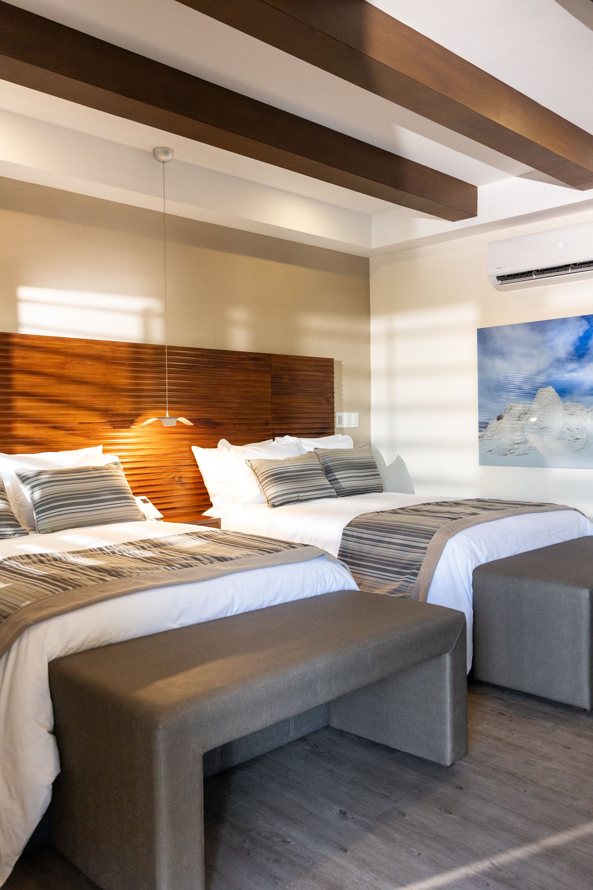 Una habitación de hotel con dos camas y un banco.