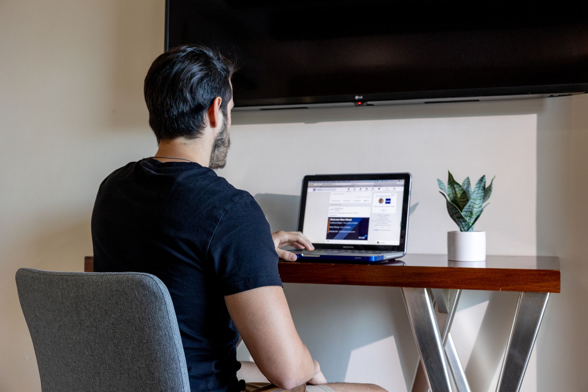 Un hombre está sentado en un escritorio utilizando una computadora portátil.
