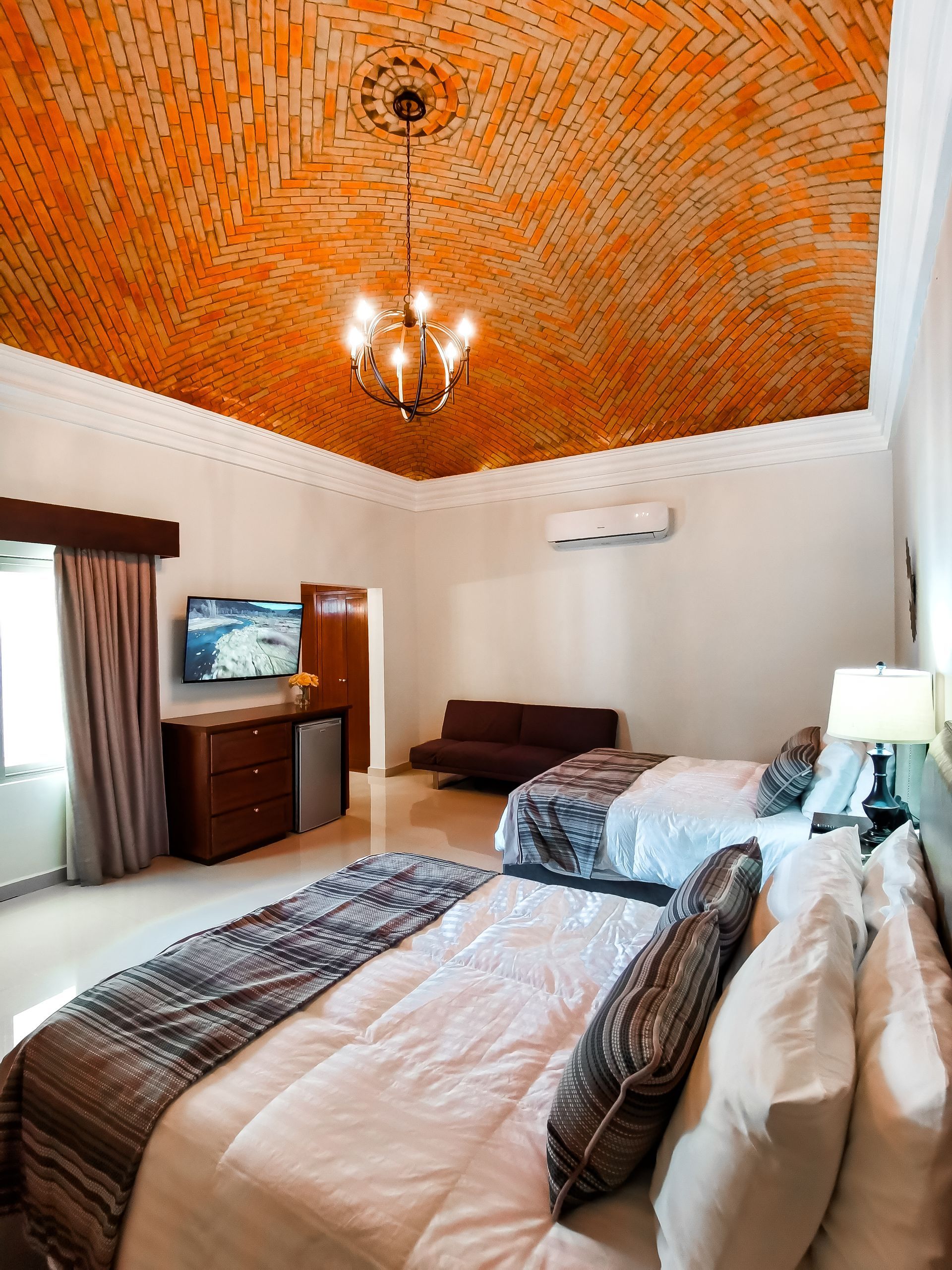Una habitación de hotel con dos camas y un techo de ladrillo.