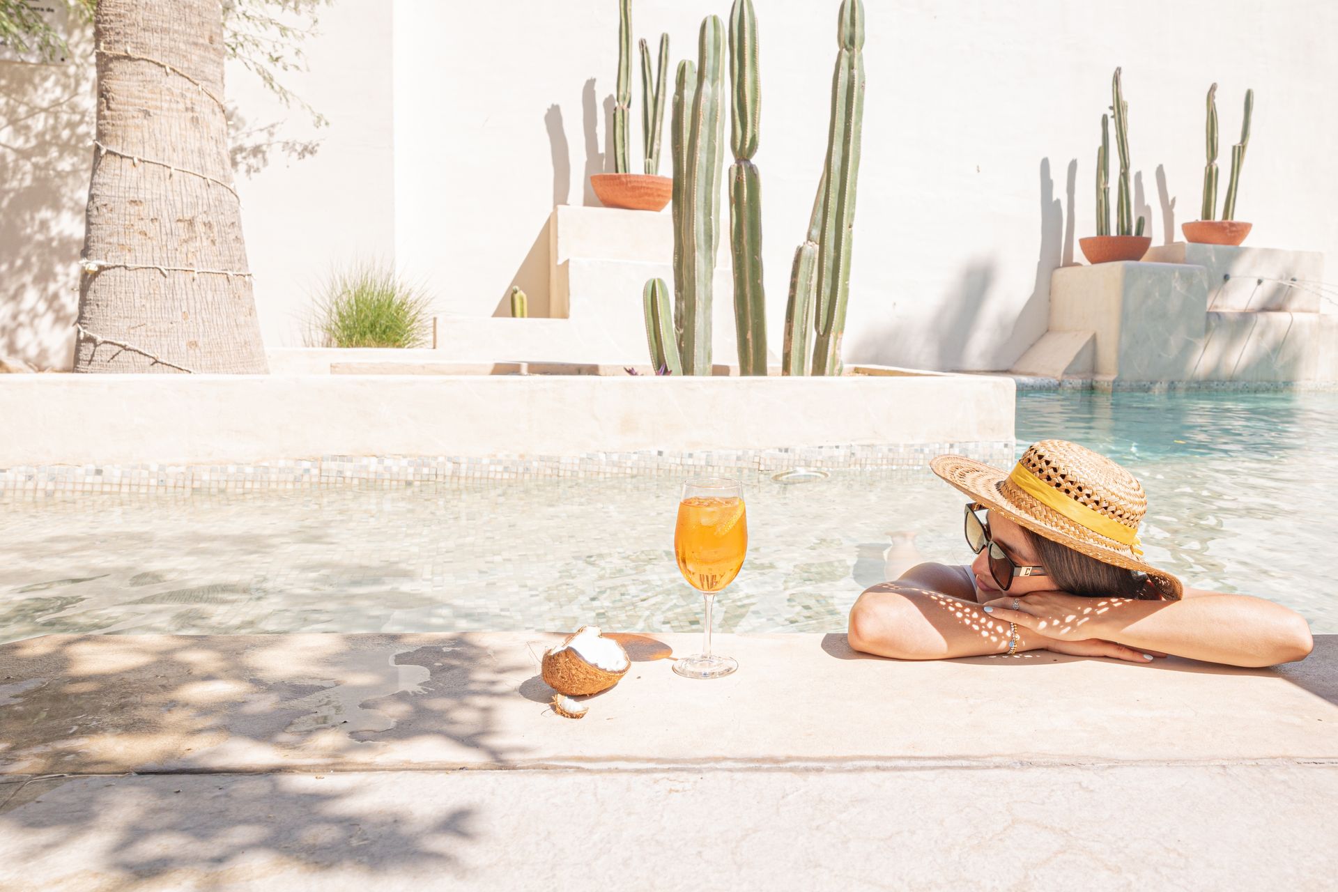 Una mujer está tumbada en el borde de una piscina con una copa de vino.
