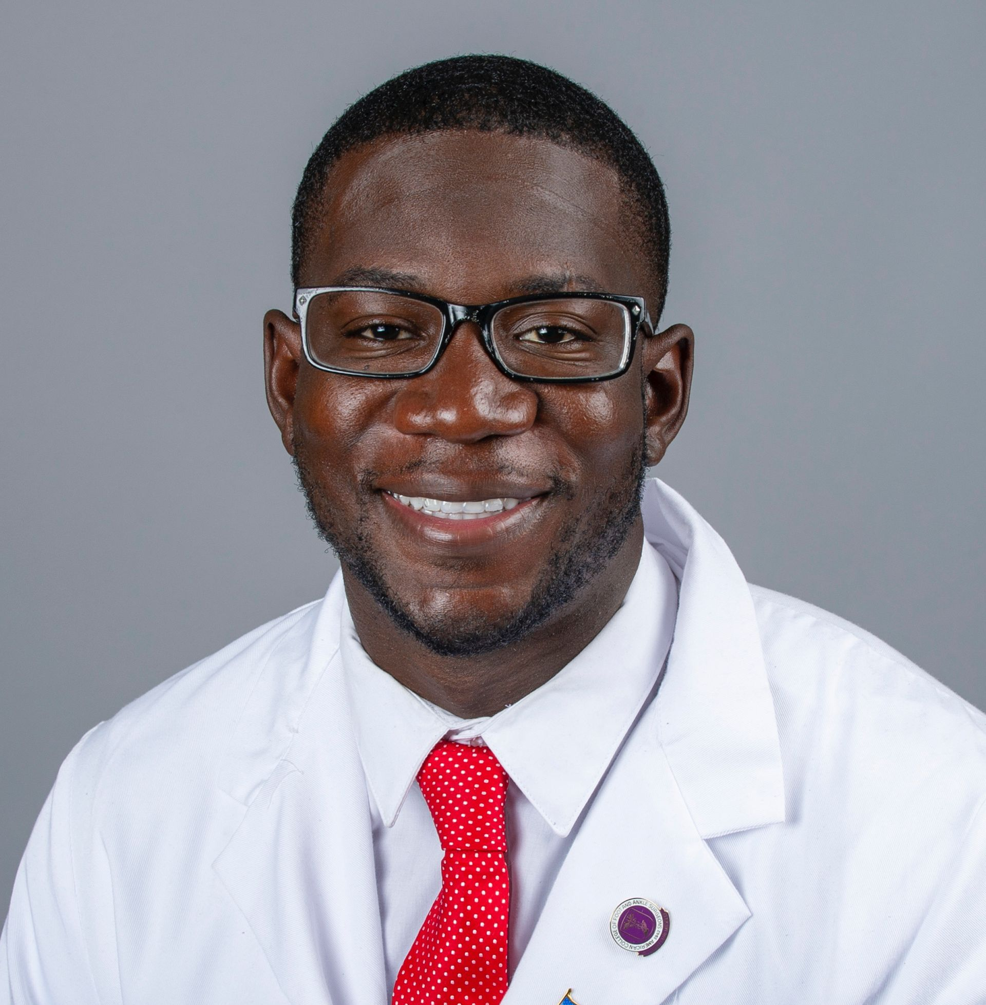 A smiling doctor in a lab coat with a stethoscope around his neck.