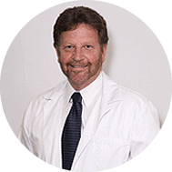 A smiling doctor in a lab coat with a stethoscope around his neck.