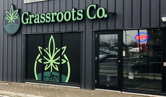 Grassroots Co. storefront with cannabis leaf logo and open sign.