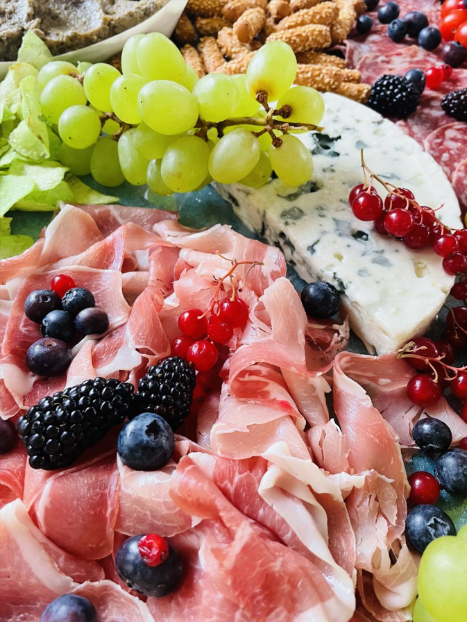 Planche de charcuterie avec raisins, prosciutto, baies et fromage.