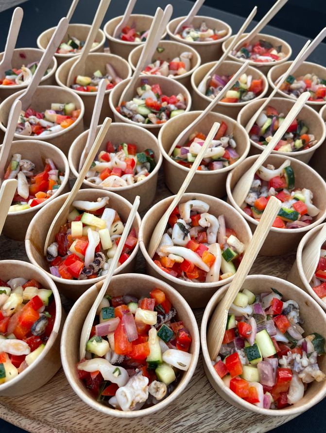 Petits gobelets en papier remplis de salade hachée colorée, chacun avec une cuillère en bois.
