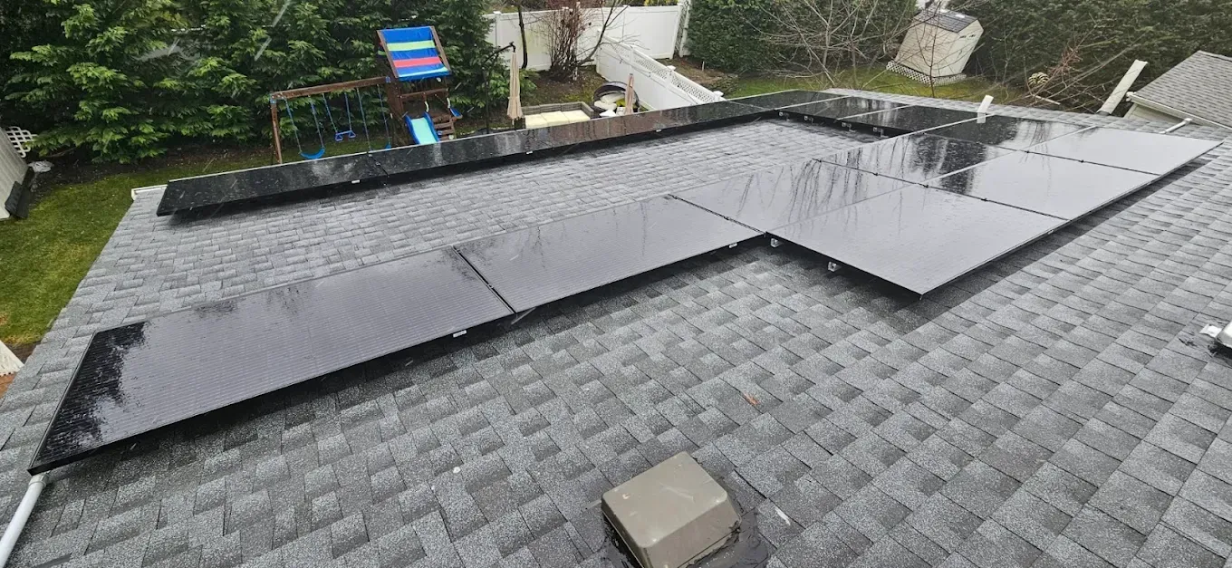 Solar panels mounted on a residential roof in a rainy backyard scene