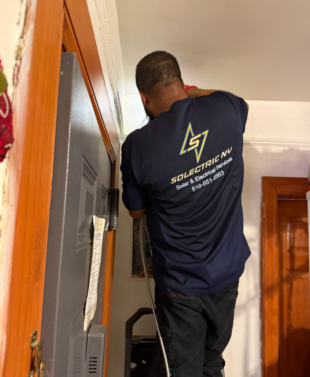 Hands using a screwdriver to install an electrical outlet in a wall box.