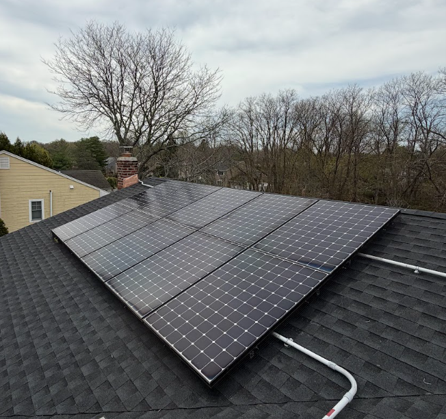 Backyard with white fence in front of a house with rooftop solar panels