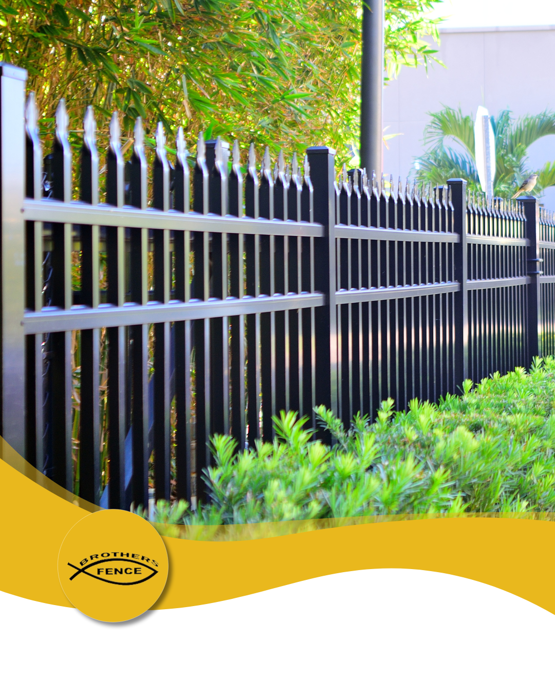 Black metal fence with pointed tops, green foliage, and yellow accent.