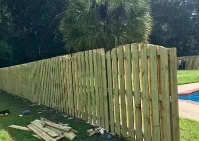Wooden fence in a yard with a pool, green boards.