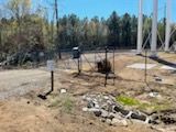 A dirt area with a gate and sign, and a water tower in the background.