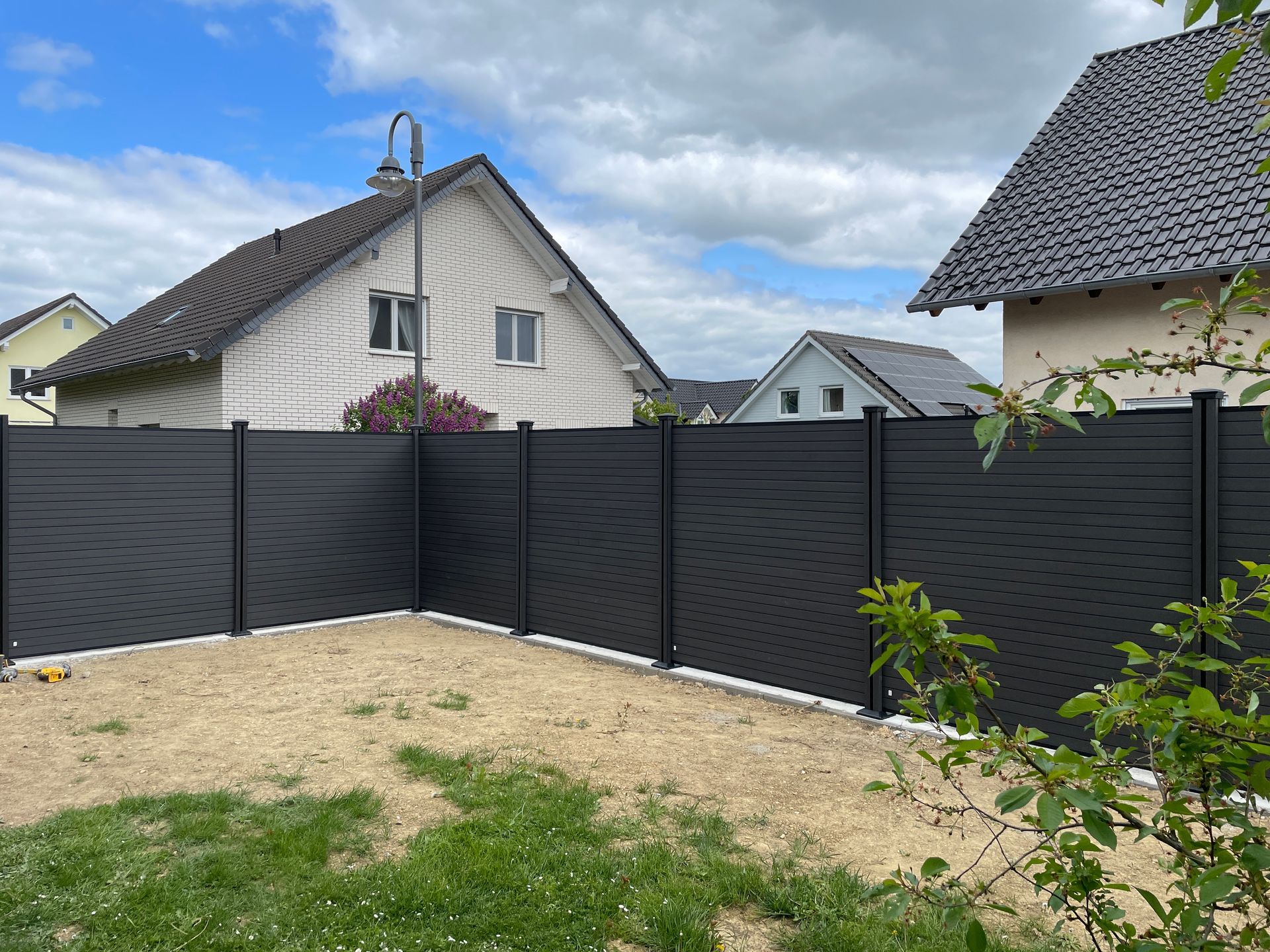 Wooden horizontal slat fence in a grassy yard with small shrubs.