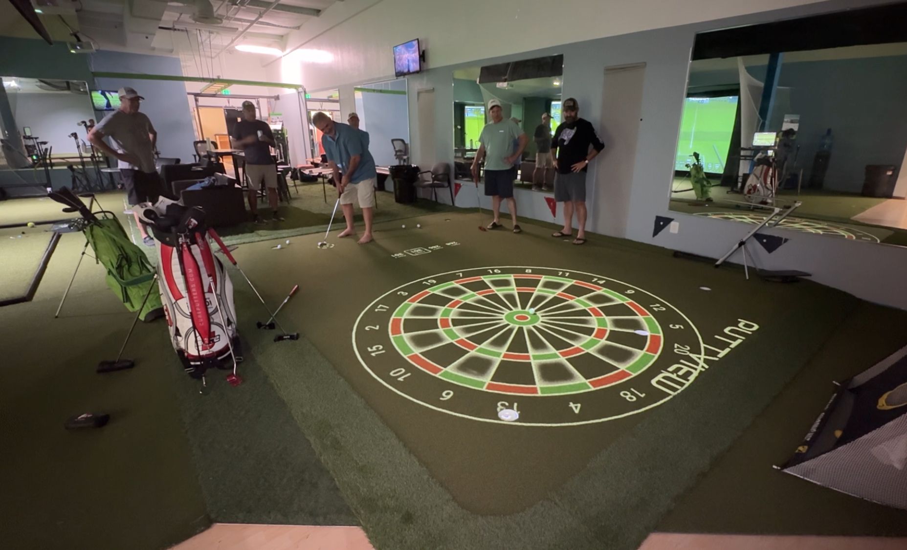 People playing indoor darts on a large floor dartboard in a game room