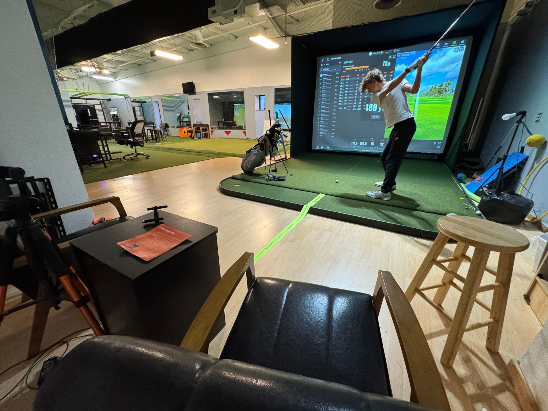 Trackman Indoor golf simulator bay with golfer swing to a large projection screen