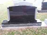 Black granite headstone with light gray accents, outdoors.