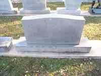 Gray granite headstone in a grassy setting.