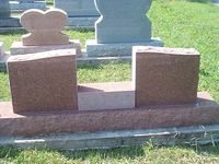 Red granite tombstone with two upright blocks and a central rectangular area.
