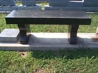 Black granite bench in a grassy cemetery.