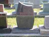 Black and brown granite tombstone with a curved top in a graveyard.