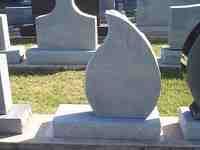 Tear-shaped headstone made of light-colored stone, in a cemetery.