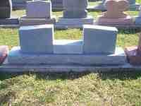 Gray granite double tombstone on grassy ground.