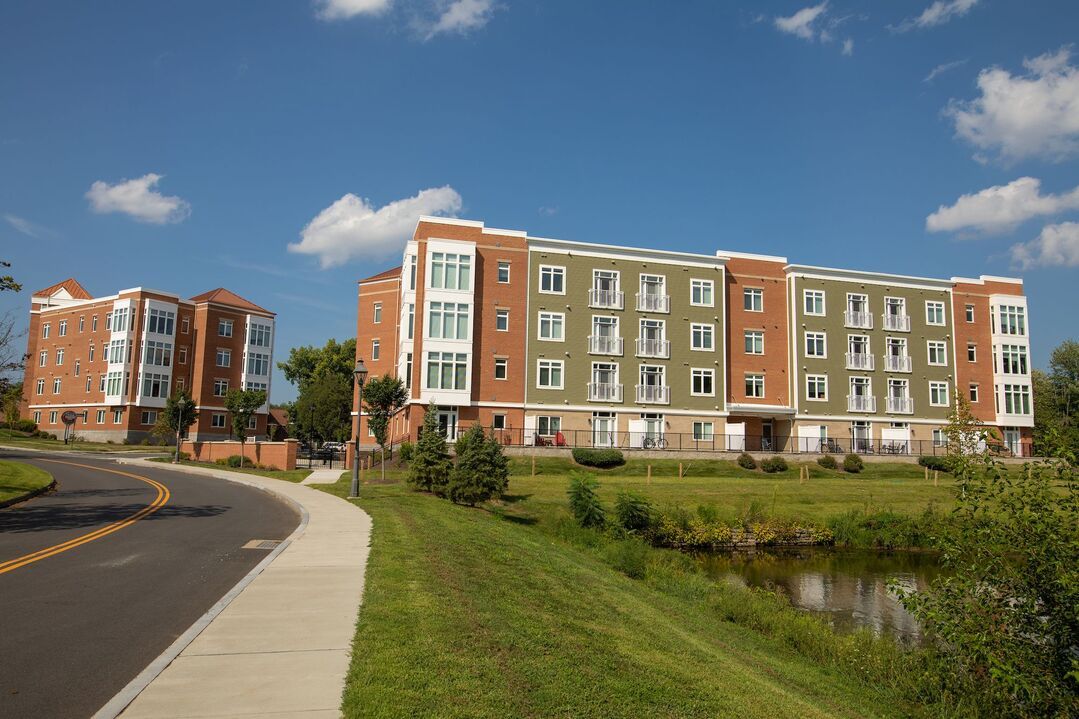 A large apartment building with a pond in front of it