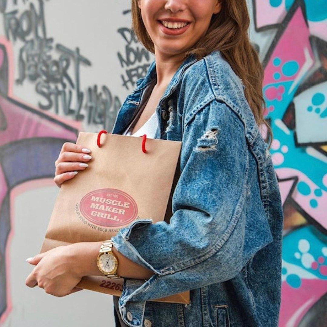 Woman holding Muscle Maker Grill Bag