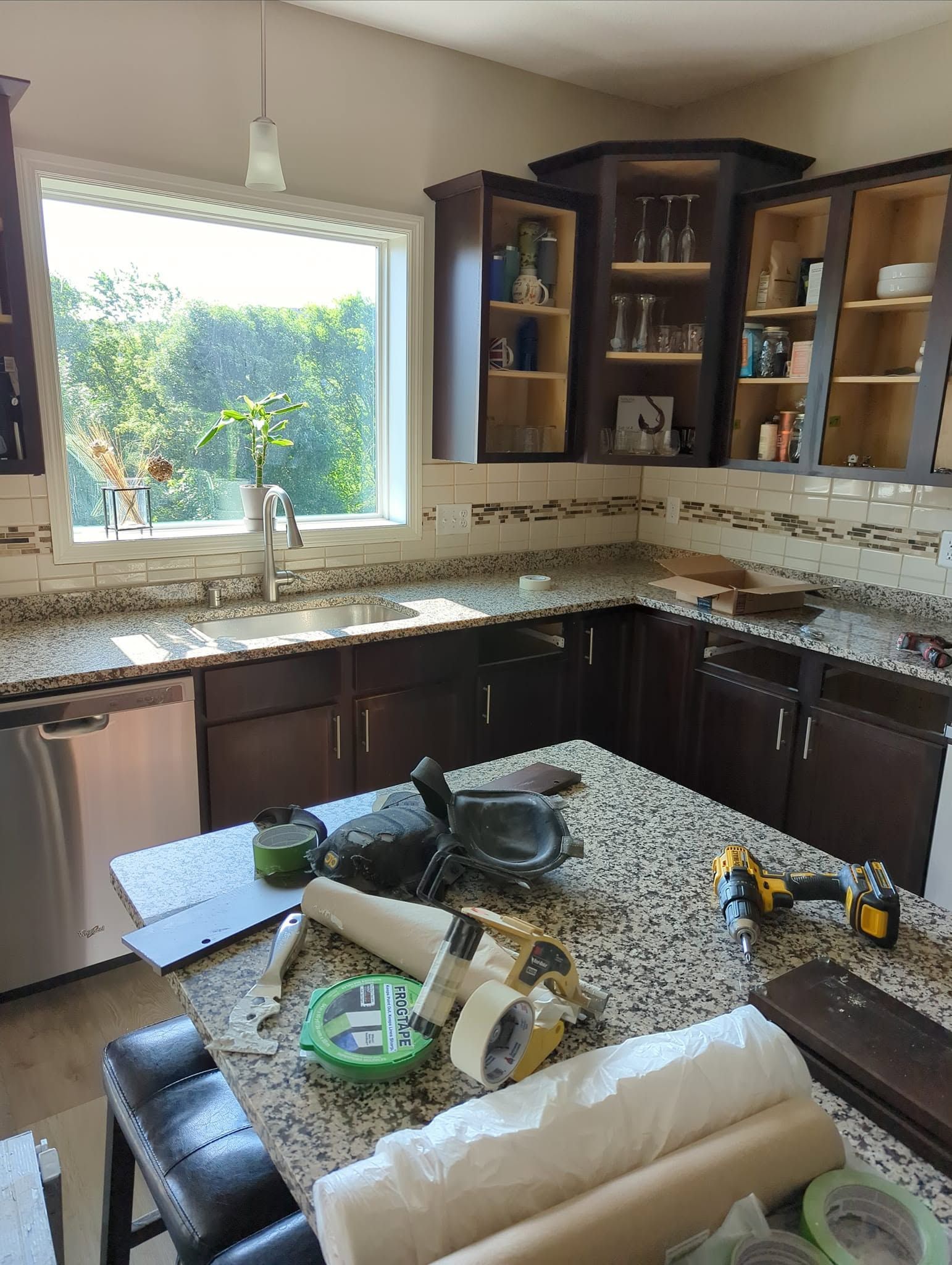 Sunlit kitchen with dark wood cabinets, granite counters, and an island set with a table runner and decor.