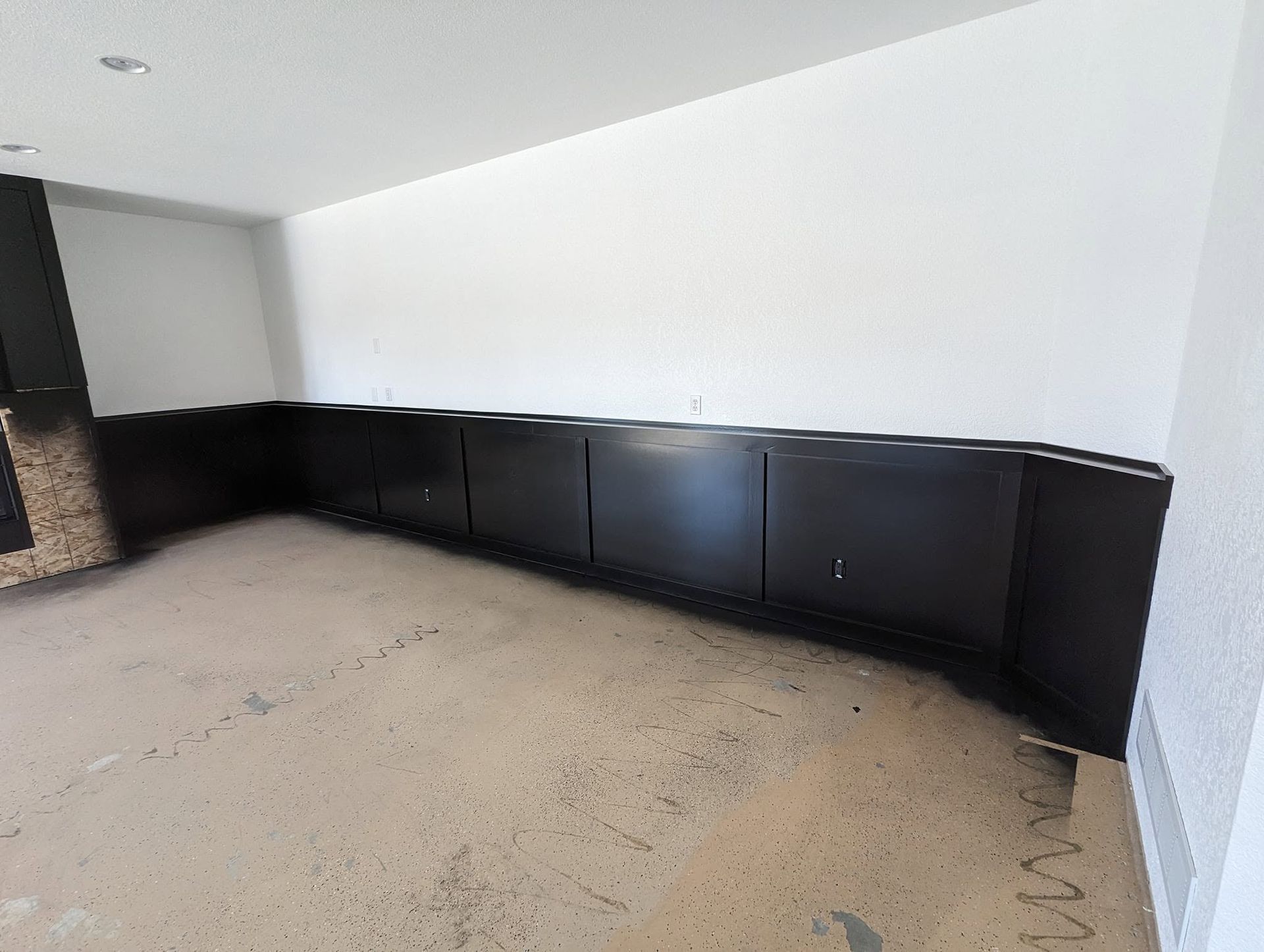 Empty room with beige carpet and black built-in cabinets along a white wall.
