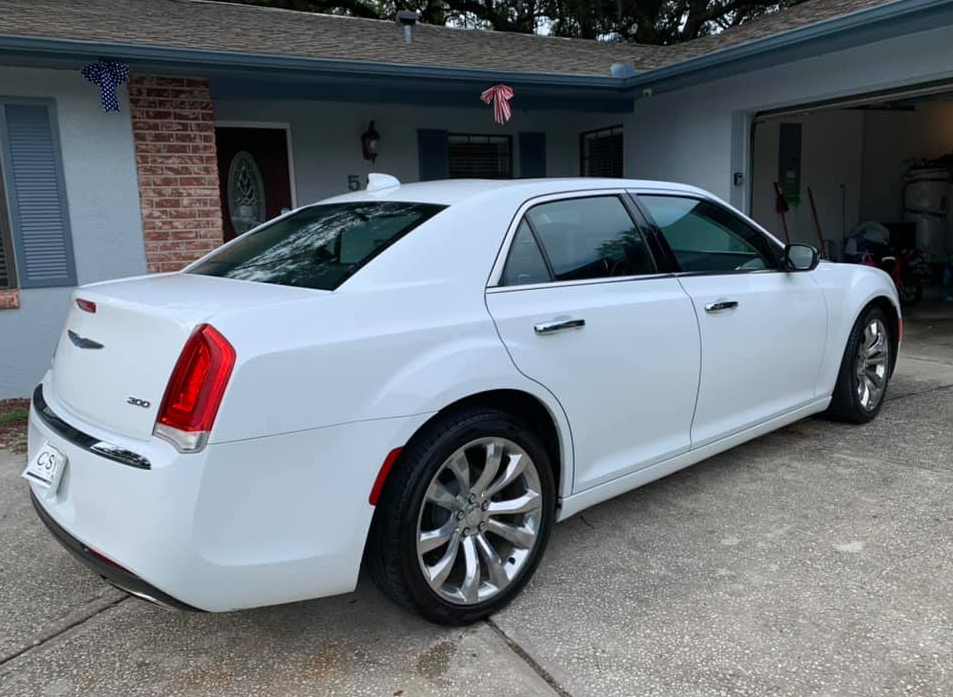 White Chrysler 300 sedan parked in front of a house with a garage.