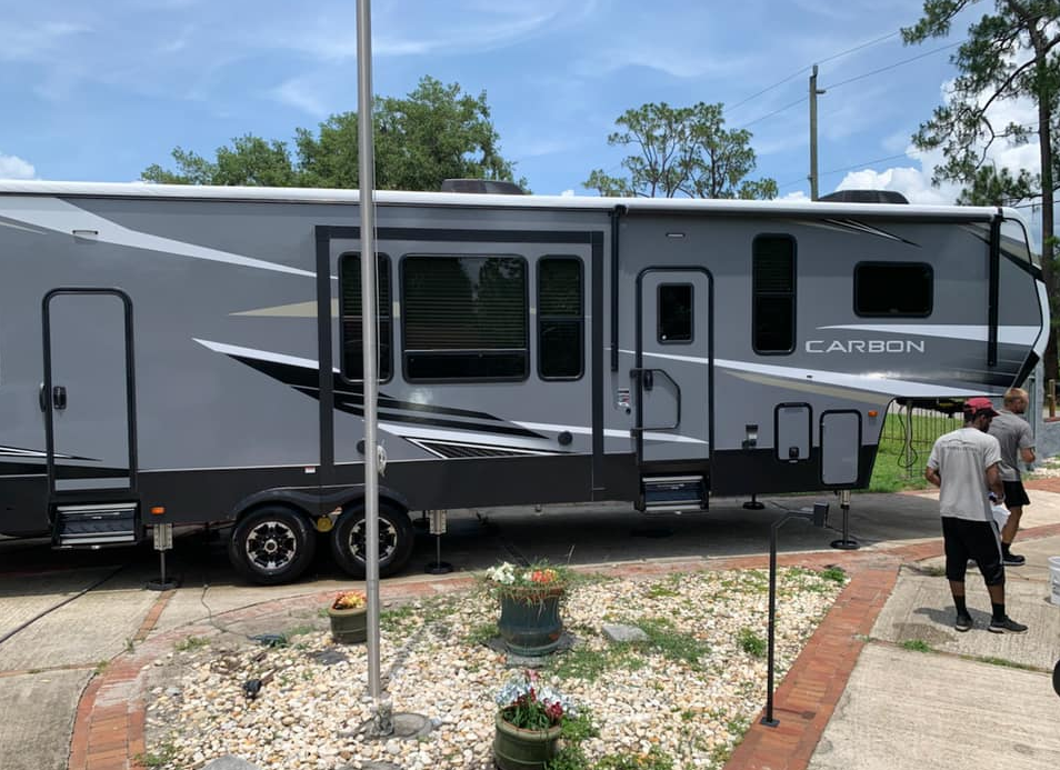 Gray Carbon RV parked outside, two men in the background.
