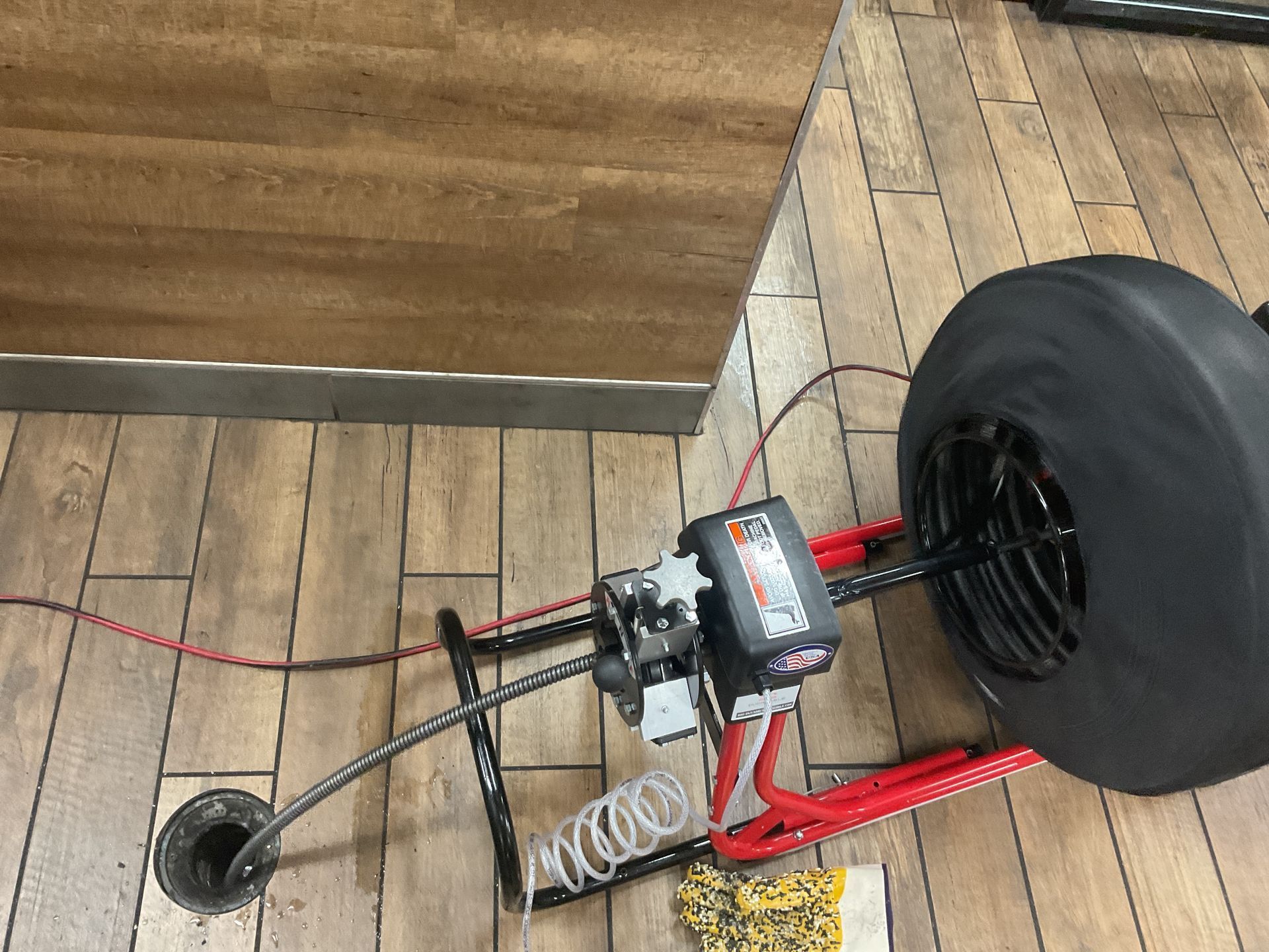 A drain cleaner is sitting on a wooden floor next to a table.