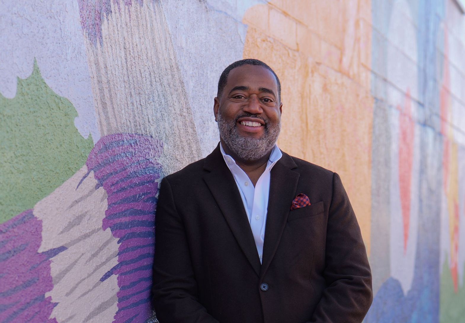 Man standing near colorful wall smiling