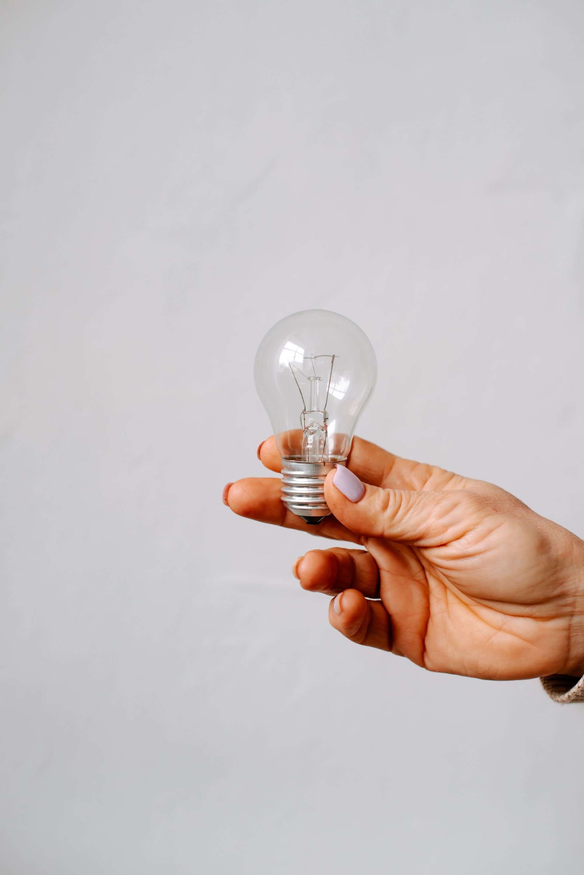 Hand holding light bulb on simple background