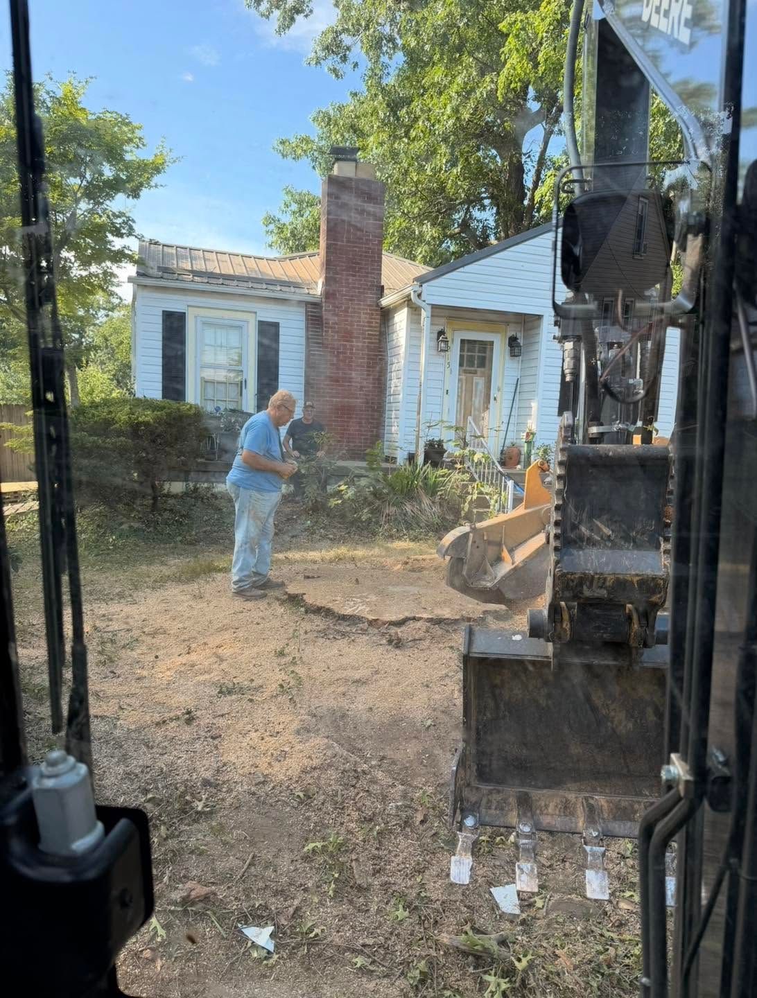 Backyard demolition scene with excavator, worker, and a small white house with chimney.