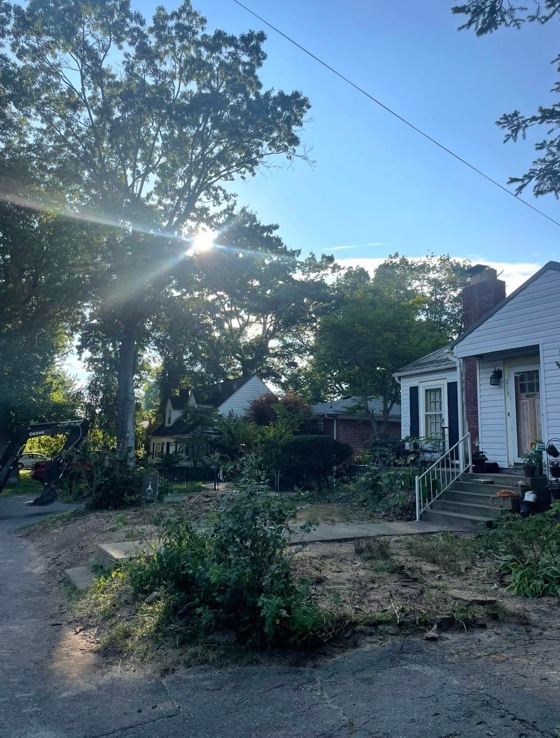 Sunlit yard with a white house, trees, and a small garden at dusk