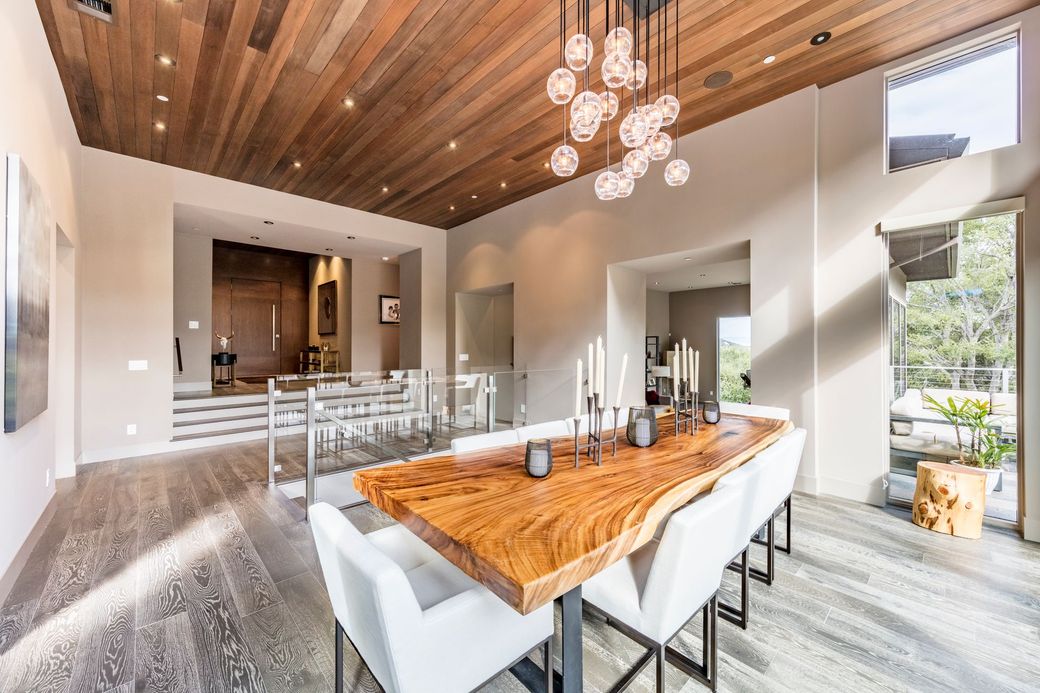 A large dining room with a wooden table and white chairs.