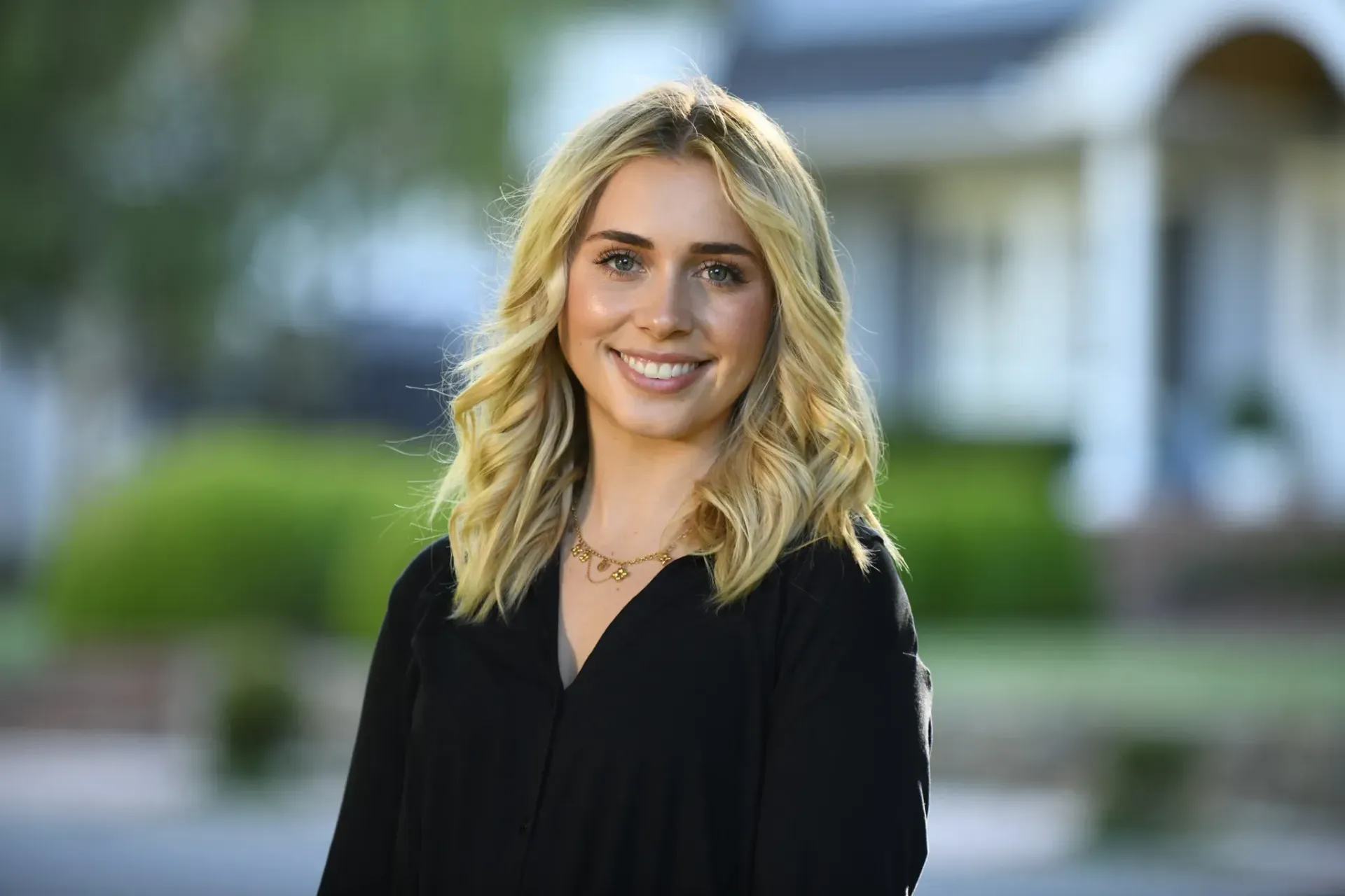 A woman wearing a black jacket and a blue shirt is smiling for the camera.