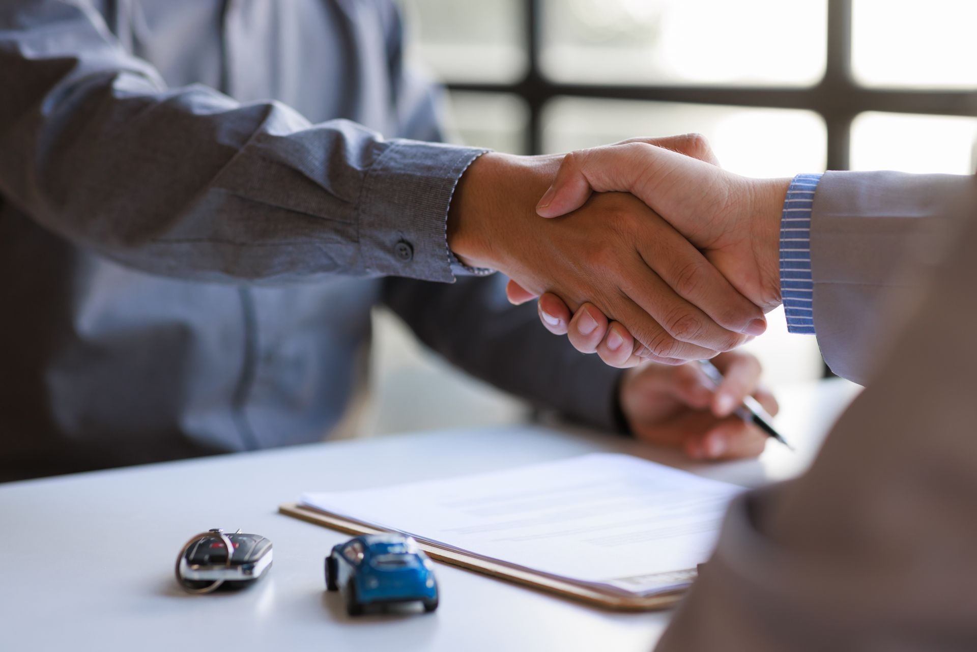 Un uomo e una donna si stringono la mano per firmare un contratto di leasing di un'auto.