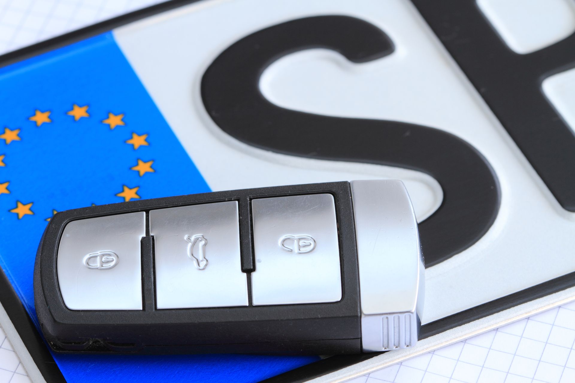 Una chiave di un'auto è appoggiata sopra una targa che dice st