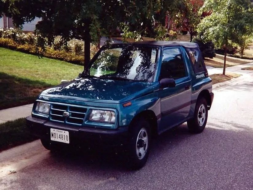 Teal compact SUV parked on a tree-lined residential street in daylight