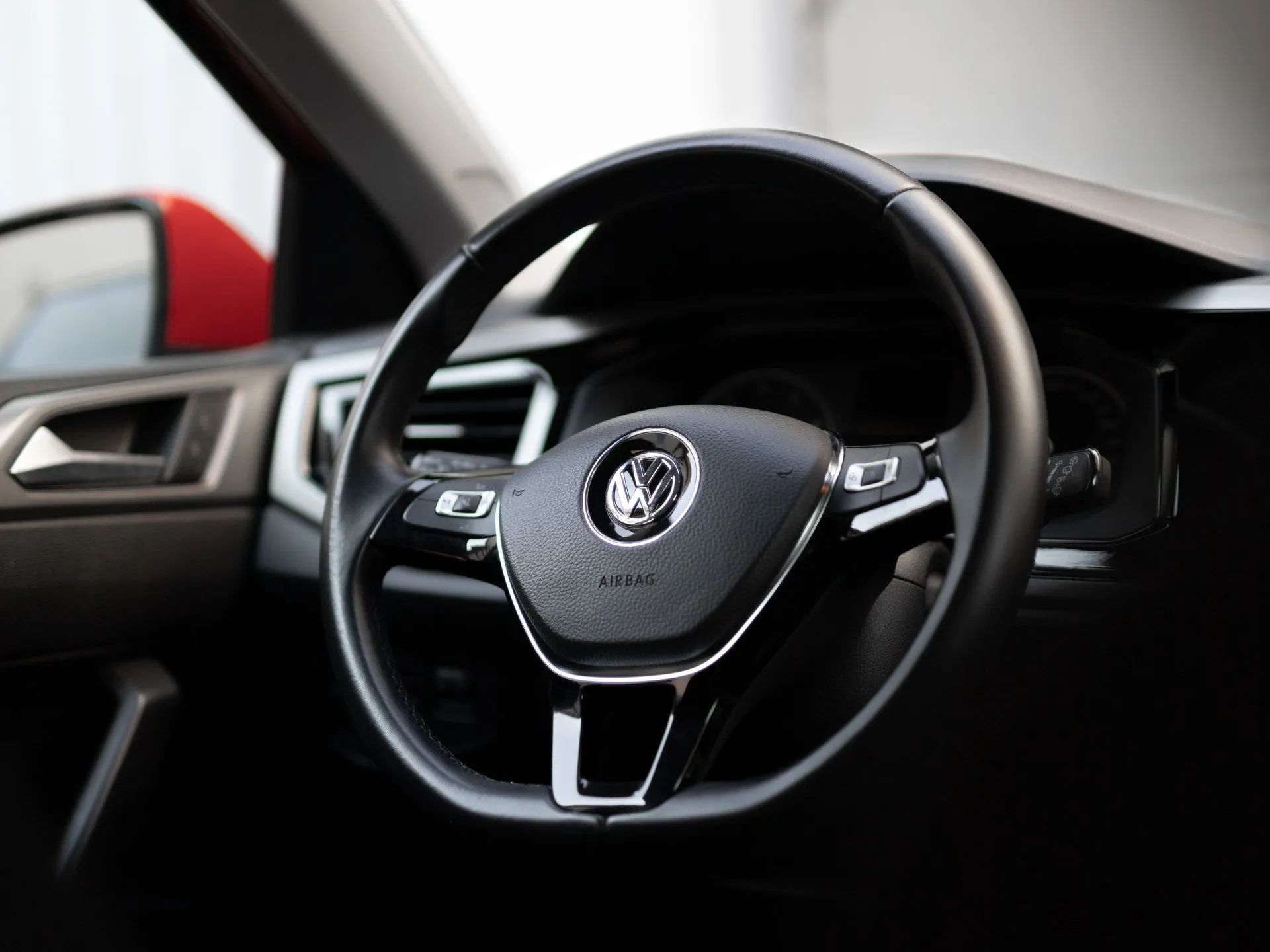 Car interior with black steering wheel and dashboard, viewed from the driver’s seat