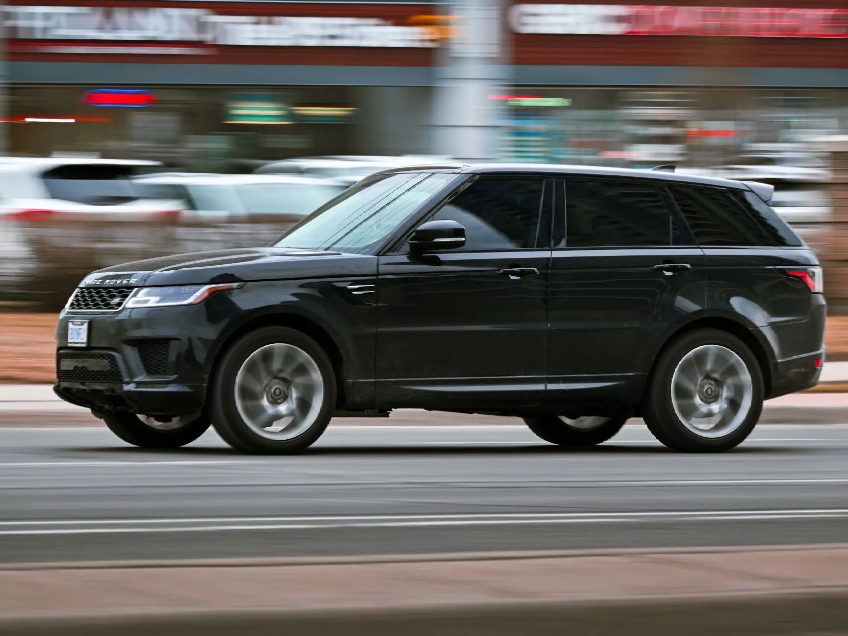 Black SUV driving fast on a city street, with motion blur in the background