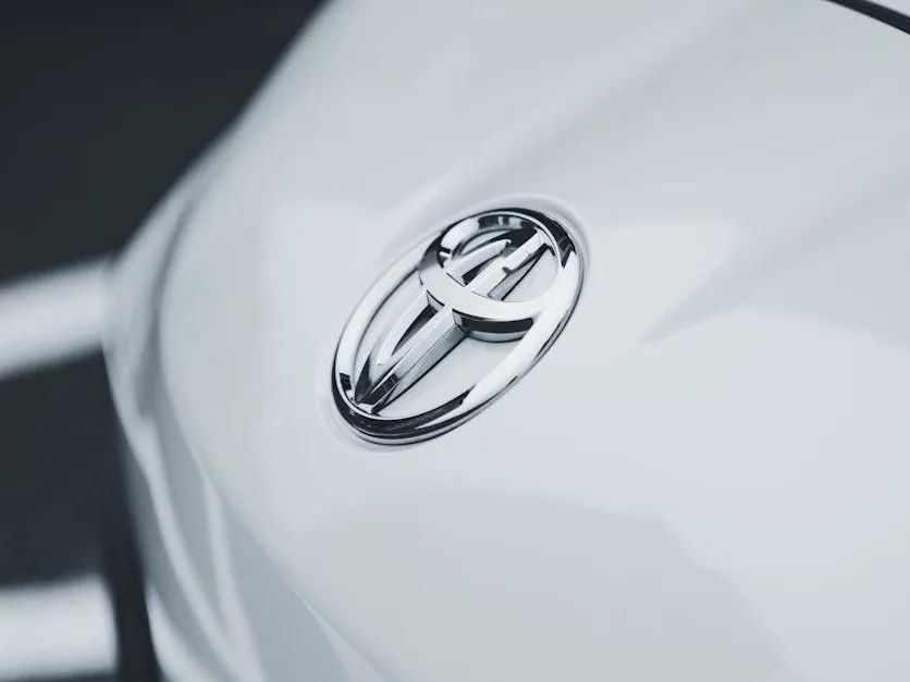 Close-up of a silver Toyota emblem on a white car hood