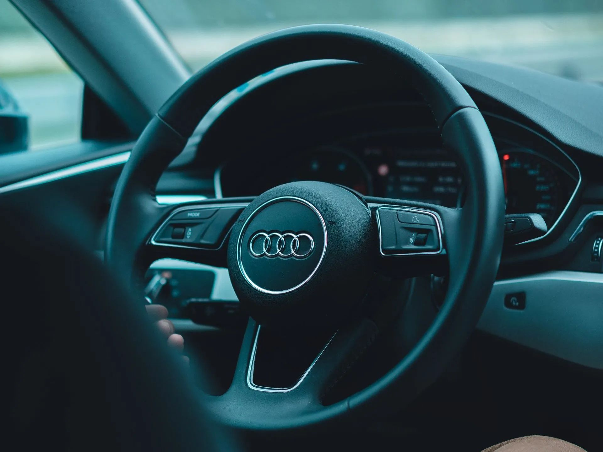 Audi steering wheel and dashboard in a car interior, lit with cool blue tones